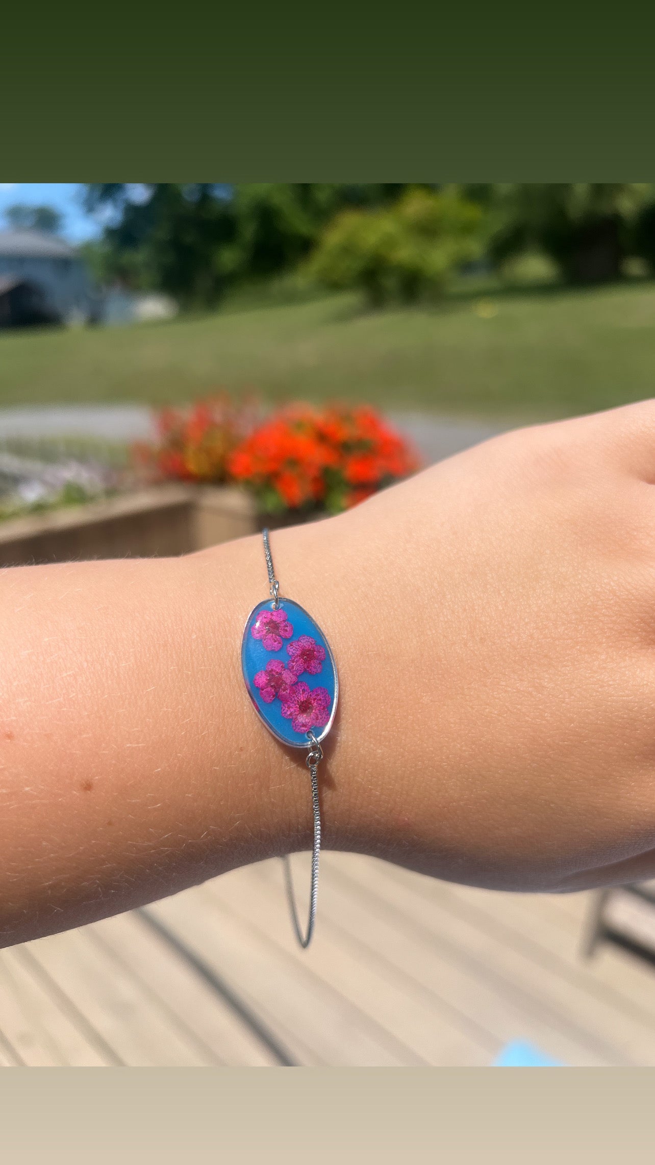 Bright blue with pink forget-me-not. Silver color adjustable bracelet.